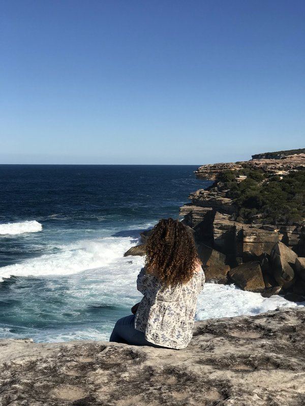 Abigail sitting on the cliffs above the ocean